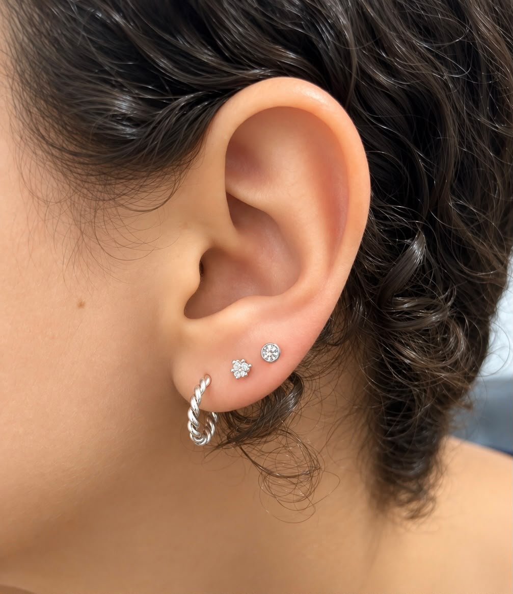 Orelha de adulto com brincos e piercings delicados em ouro
